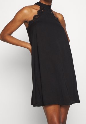 Robe noire à bretelles en tissu léger, avec des détails en dentelle au niveau du col et des emmanchures, dotée d'une silhouette ample et fluide.