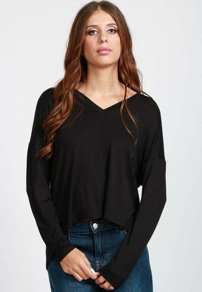 Maglietta nera a maniche lunghe con scollatura a V e vestibilità rilassata; realizzata in materiale morbido; design cropped con maniche ampie; abbinata a jeans a vita alta.