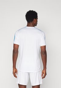 Hvit sportsdrakt med blå detaljer på skulderen, laget av lett materiale, med korte ermer og rund halsdesign.