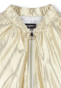 Veste bomber dorée claire en tissu brillant avec col froncé, fermeture éclair à l'avant et doublure blanche. Comprend une étiquette à l'intérieur.