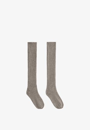 Paire de longues chaussettes grises côtelées, posées à plat, conçues pour couvrir les mollets et les pieds, sur fond blanc.