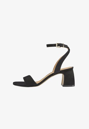 Sandales à talons en suédine noire avec une large sangle avant et une sangle de cheville comportant une boucle en métal doré. Talon carré et texture lisse, mate.