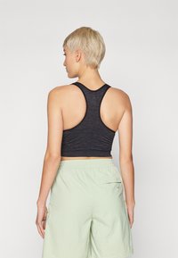 Μαύρο εφαρμοστό αθλητικό σουτιέν με σχέδιο racerback, ριγέ υφή, συνδυασμένο με ανοιχτό πράσινο σορτς με ελαστική μέση και πλαϊνή τσέπη.