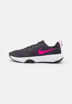 Zapatilla de running Nike negra y púrpura oscuro con logo Swoosh de color rosa brillante y suela blanca, mostrada de lado sobre fondo blanco.