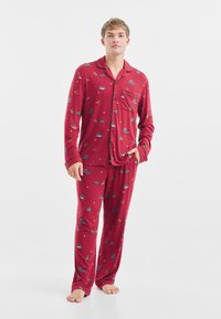 Rode pyjama set gemaakt van zachte stof, met een knoopsluiting overhemd met een zak en lange mouwen, gecombineerd met loszittende broek met kleurrijke patronen.