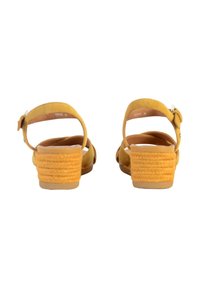 Sandali in suede giallo con tacco basso intrecciato. Apertura sul retro e cinturino alla caviglia regolabile con una fibbia metallica. Interno liscio.