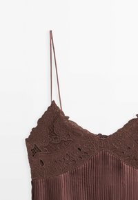 Bruine geplooide top met verstelbare spaghettibandjes en ingewikkelde kantdetails bij de halslijn, met een gestructureerde afwerking.