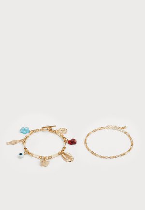 Bracelets en tonalité dorée : l'un avec des charms (poisson, papillon, cœur, fleur bleue) et l'autre avec un design de chaîne simple.