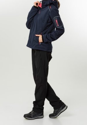 Marinblå fleecejacka med rosa detaljer och huva, kombinerad med svarta byxor och mörka utomhusskor, med en sidoficka med dragkedja på jackan.