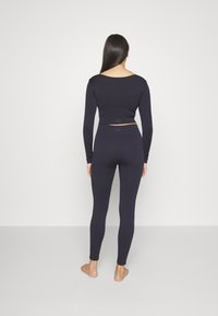 Marinblå långärmad kort topp och högmidjade leggings i ribbat tyg, med en minimalistisk design utan framträdande detaljer eller accenter.