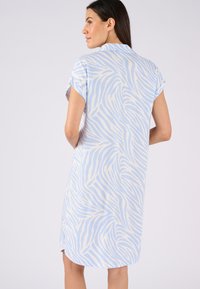 Abito a maniche corte di colore azzurro chiaro con strisce zebrate bianche. Tessuto liscio, lunghezza al ginocchio, con taglio dritto e spacchi laterali.