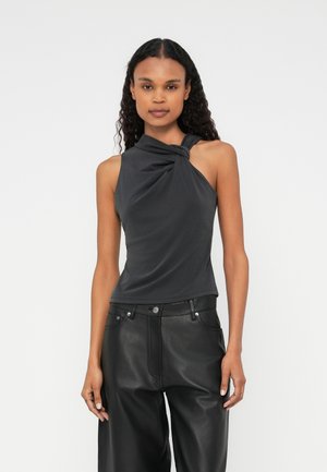 Grijze mouwloze top met een gedraaide stofdetail aan de halslijn, gecombineerd met zwart leren broek met hoge taille. Gladde textuur.