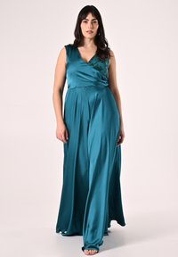 Tuta color teal in raso con design a incrocio, senza maniche e un dettaglio ricamato sullo scollo. Silhouette fluida con gambe larghe.