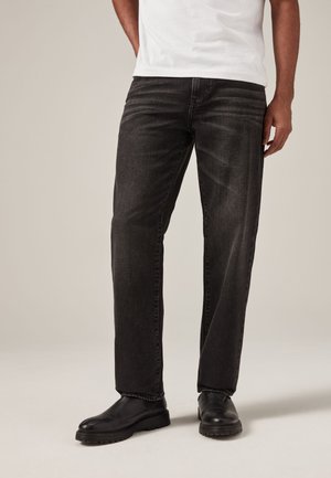Zwarte denim jeans met een rechte pasvorm, voorzien van een vijf-pocket ontwerp, subtiele stikdetails en omgeslagen broekvoeten, gecombineerd met zwarte schoenen.