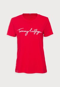Röd bomullströja med en vit broderad logotyp på framsidan. Klassisk rund hals och korta ärmar. Slät textur och normal passform.