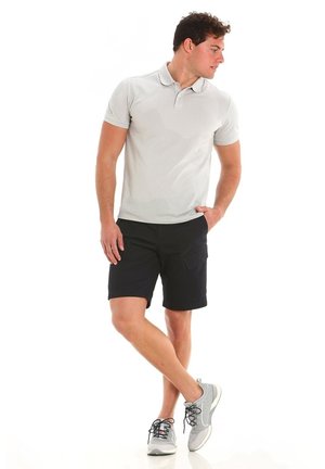 Polo shirt grigio chiaro a maniche corte, abbinato a pantaloni corti neri e sneakers grigie. La maglietta presenta un design con colletto.