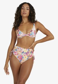 Conjunto de bikini floral con un patrón de flores multicolores. La parte superior tiene una forma clásica con tirantes anchos, y la parte inferior de talle alto cuenta con detalles de lazo.