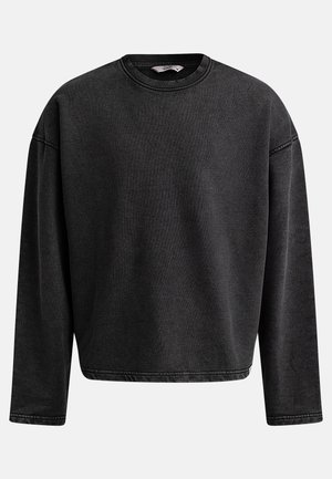 Black oversized sweatshirt with long sleeves, round neckline, and ribbed texture. Features reinforced stitching at the cuffs and hem.