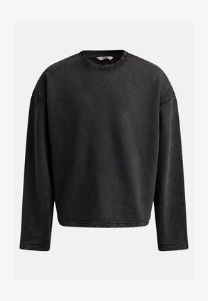 Melna pārspīlēta sporta krekls ar garām piedurknēm, apaļu izgriezumu un ribotu tekstūru. Iekļauta pastiprināta šuvju apstrāde piedurkņu un apakšmalas daļā.