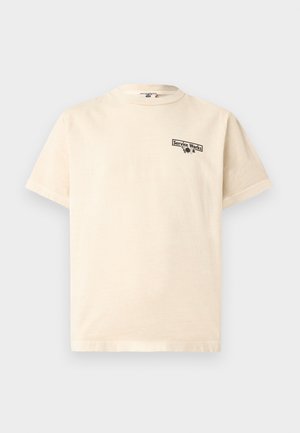 Beżowy T-shirt z krótkim rękawem, okrągłym dekoltem oraz małym czarnym napisem i grafiką "Service Works" po lewej stronie klatki piersiowej.