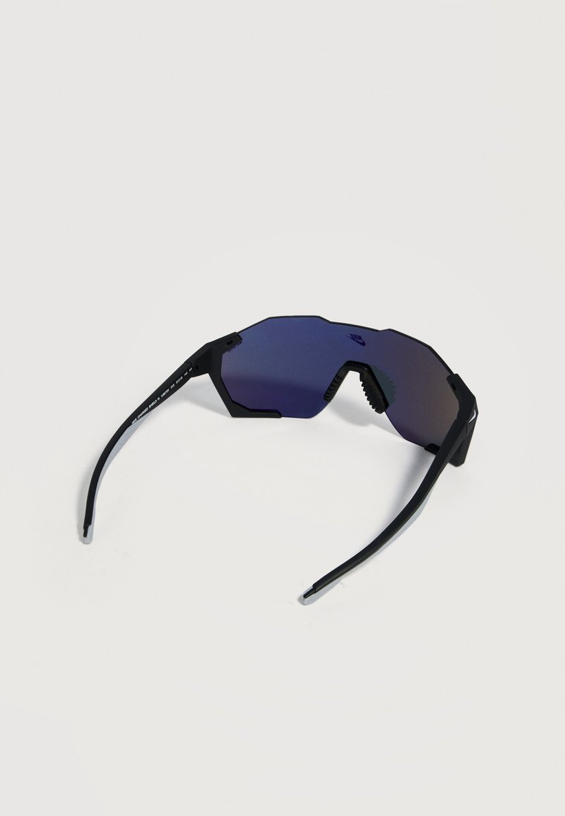 Schwarze Sportsonnenbrille mit einer breiten, blau getönten Linse und schrägen Bügeln, auf weißem Hintergrund platziert.