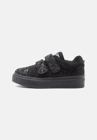 Sneaker nera bassa con suola spessa, ricoperta di piccoli chiodini luccicanti, dotata di due ampie fasce in velcro per la chiusura.