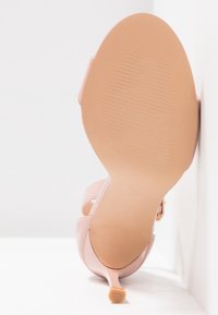 Sandale à talons hauts rose avec une finition lisse et brillante. Dispose de deux brides et d'un bout pointu. La semelle est texturée, avec un talon fin.