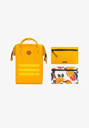 Mochila amarilla con dos bolsillos; uno de color amarillo sólido con una cremallera negra y otro con un patrón floral naranja. Incluye un asa y correas.