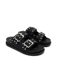 Sandales noires à semelle plate avec des boucles en métal argenté, des détails cloutés et un design à bout ouvert, fabriquées dans un matériau doux.