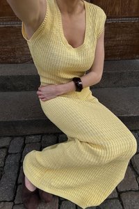 Geltona megzta suknelė su V formos iškirpte ir trumpomis rankovėmis, turinti vertikalią ribotą tekstūrą, priglundantį siluetą ir iki kelių ilgio.