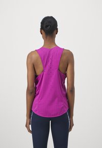 Bezrekawnik sportowy w żywym kolorze magenta z perforowanymi detalami, zaokrąglonym dołem i luźnym krojem dla lepszej przewiewności.