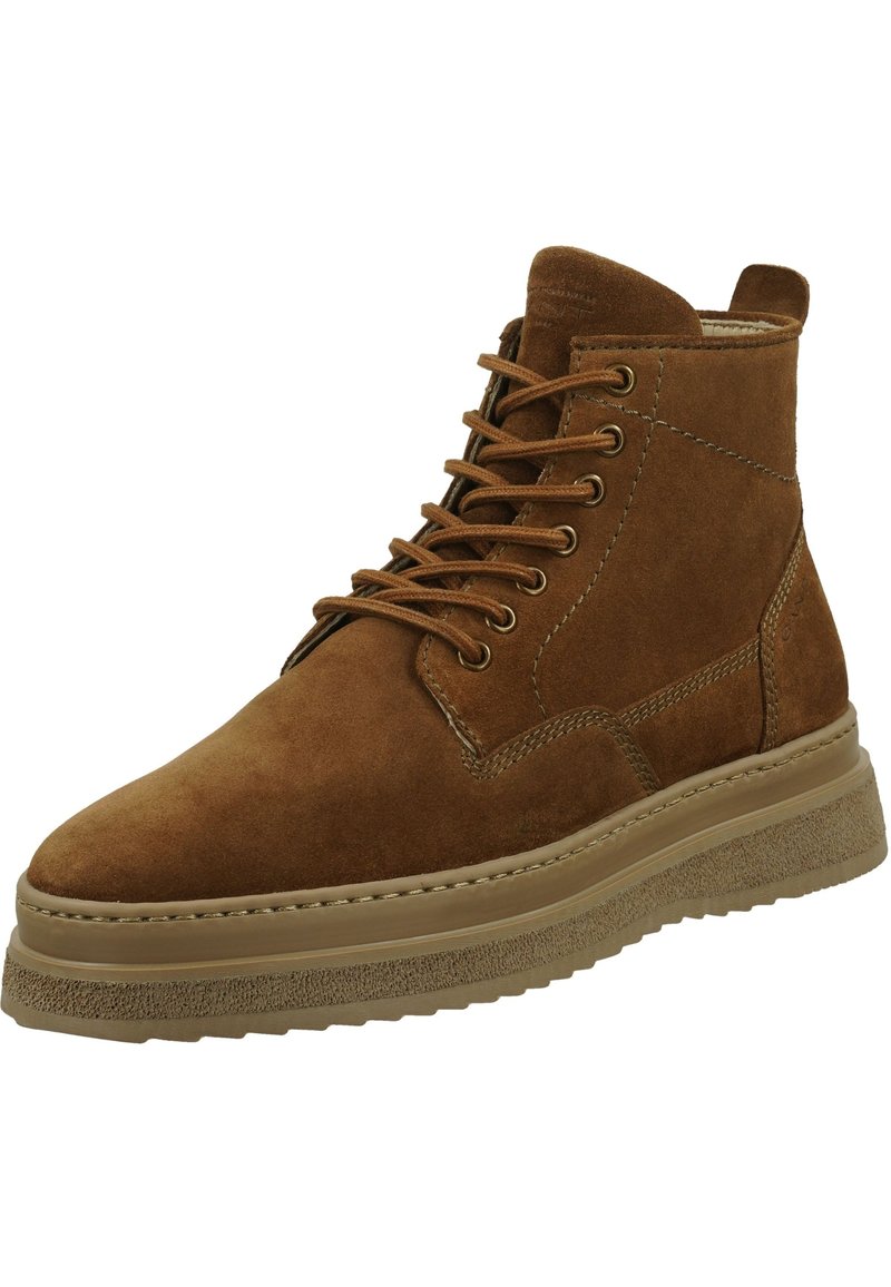 Bottines en daim marron avec un bout arrondi, un laçage à l'avant et une semelle en caoutchouc texturée. Présente des coutures discrètes et un col rembourré.