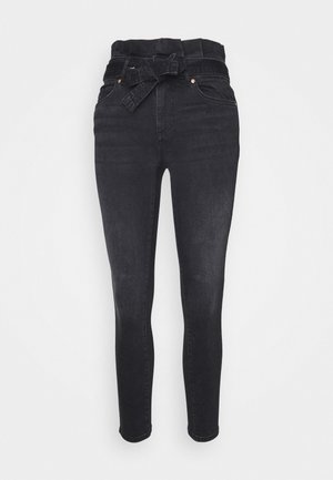 Zwarte skinny jeans met hoge taille, paperbag-taille en een bijpassende stoffen riem die vooraan in een strik is gebonden.
