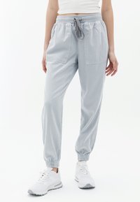 Hellgraue, leichte Jogginghosen mit elastischem Bund und verstellbarem Kordelzug. Mit zwei Fronttaschen und schmal zulaufenden Bündchen an den Knöcheln.