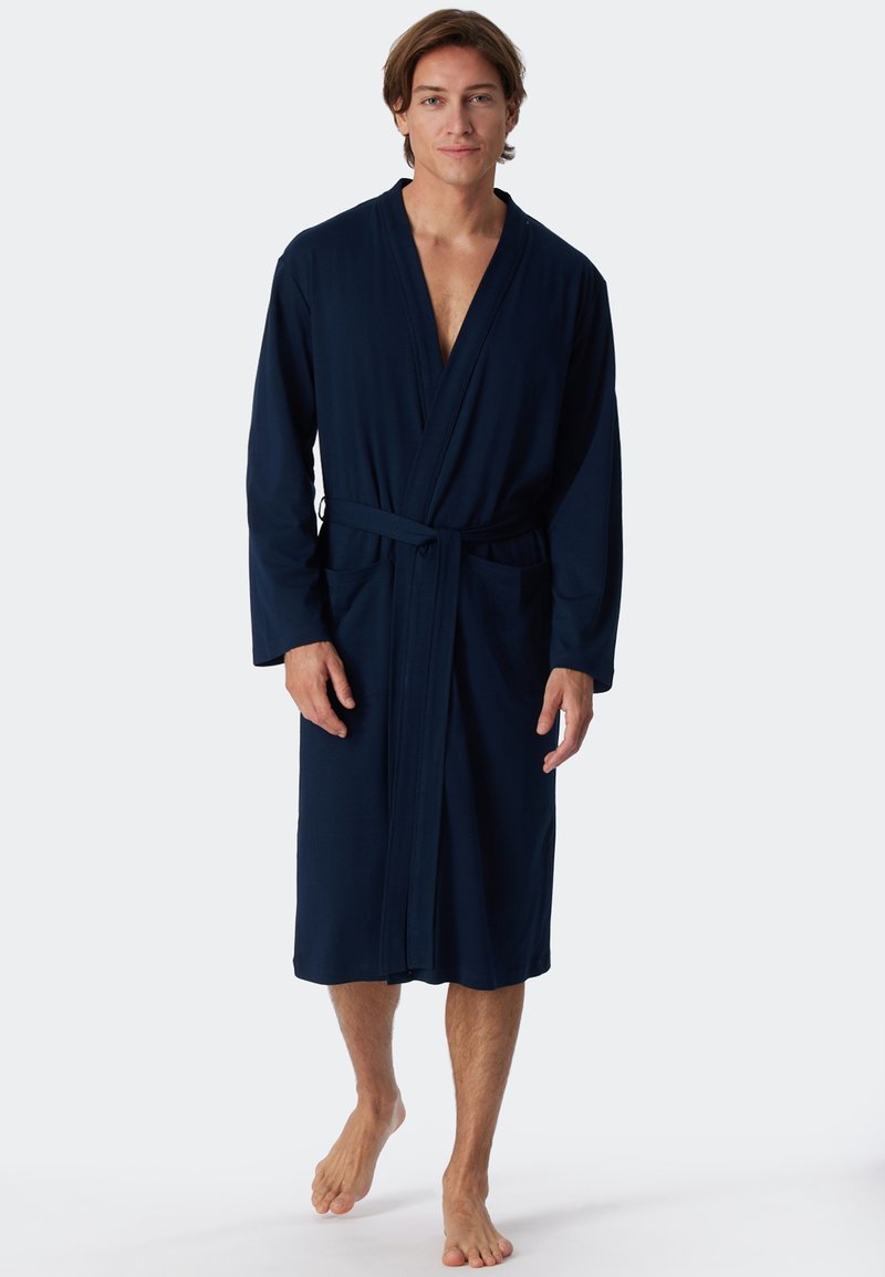 Marineblauer Bademantel aus weichem Material, mit langen Ärmeln, einem Taillengürtel und zwei vorderen Taschen. Leicht und knielang gestaltet.