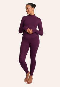 Bordeaux lange mouw top met hoge kraag, gecombineerd met bijpassende strakke leggings. Soepele textuur, rekbare stof, zachte afwerking.