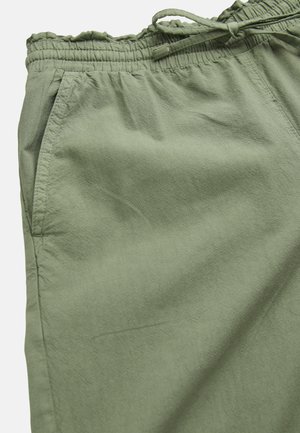 Nærbillede af olivengrønne bukser med elastik i taljen, snøre og synlig sidelomme.