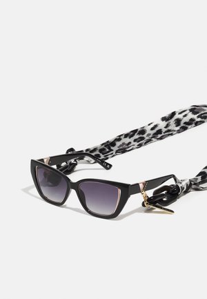 Ochelari de soare negri în stil cat-eye cu lentile gradient. Au accente aurii și o curea cu imprimare leopard alb-negru, cu un charm auriu.