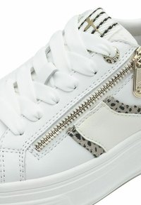 Vit lädersneaker med en texturerad sidopanel i leopardmönster och en metalldragkedjeaccent. Den har platta, vita snören och en kraftig sula.