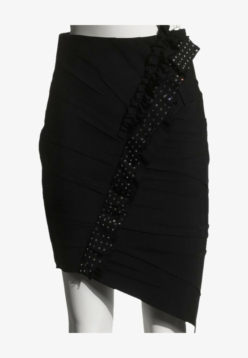 Jupe asymétrique noire avec un volant diagonal et un détail de bordure cloutée, sur un mannequin de la taille jusqu'à la moitié de la cuisse.