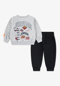Γκρι φούτερ με τυπωμένα λογότυπα «JORDAN» και μαύρο παντελόνι με ελαστική μέση. Το υλικό φαίνεται μαλακό, με ριμπ μανσέτες και άνετη εφαρμογή.