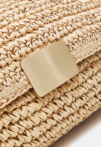 Tkaná slámová kabelka na ruku s strukturovaným béžovým povrchem a obdélníkovým uzávěrem z kartáčovaného zlatého kovu.