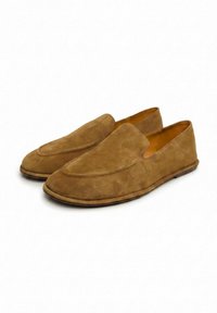 Paire de mocassins en daim marron à enfiler avec des bouts arrondis et des semelles plates et basses sur fond blanc.