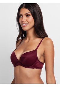Maroons gevoerde beha met dunne verstelbare bandjes en een gladde stof. Kenmerkt zich door een gewatteerde onderband en een subtiele glans op het materiaal.