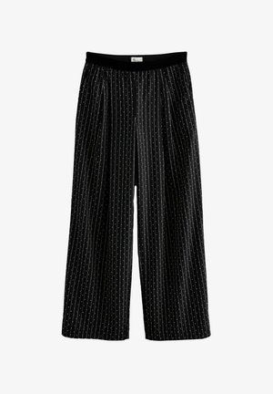 Čierne široké nohavice majú vertikálne biele pruhy a malé bodky, s čiernym elastickým pásom pre pohodlie.