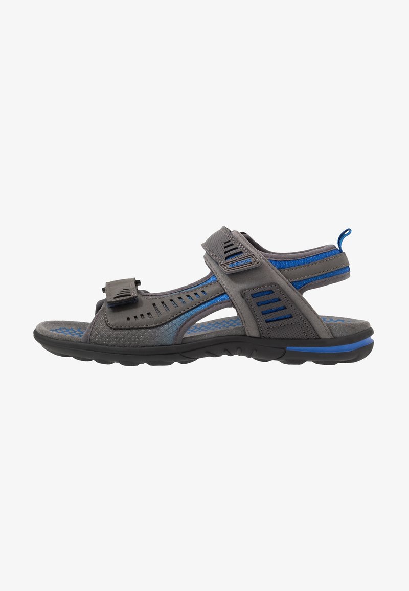 Sandale sportive pour homme, grise et bleue, à bout ouvert, avec des sangles réglables et une semelle texturée pour une utilisation extérieure.
