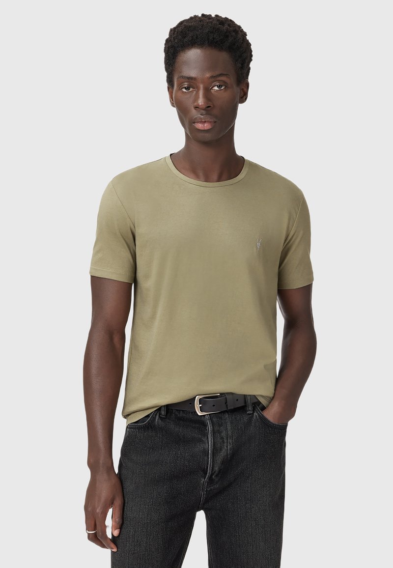 T-shirt a maniche corte verde oliva realizzato in tessuto morbido, con scollatura rotonda e un logo discreto sul lato sinistro del petto. Abbinato a jeans neri.