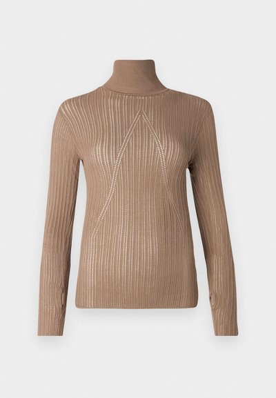 Beige neulepusero, jossa on ribbitekstuuri ja pitkät hihat. Etuosassa on kolmiomainen ommeltu kuvio lisäämässä yksityiskohtia.