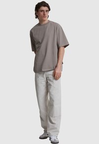 Tricou gri cu mânecă scurtă, cu decolteu rotund, asortat cu pantaloni albi, lejeri și adidași gri și albi. Design simplu, fără modele vizibile.