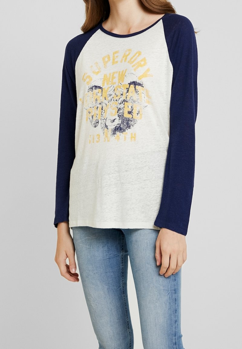Lichtgrijs en marineblauw langemouwenshirt met een ronde hals, met een vintage-stijl gele en blauwe opdruk in het midden.